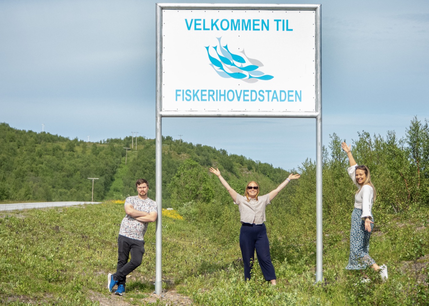 Tre personer jubler ved skiltet «Velkommen til Fiskerihovedstaden».
